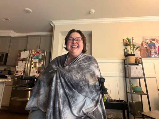 Chelsea smiling while wrapped in a gray IceBlankie CoolSleep Cooling Blanket